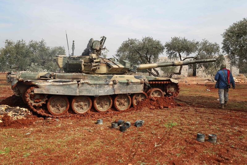 A Syrian rebel fighter walks by a tank in Syria's northern Idlib countryside amid clashes with government forces.   AFP