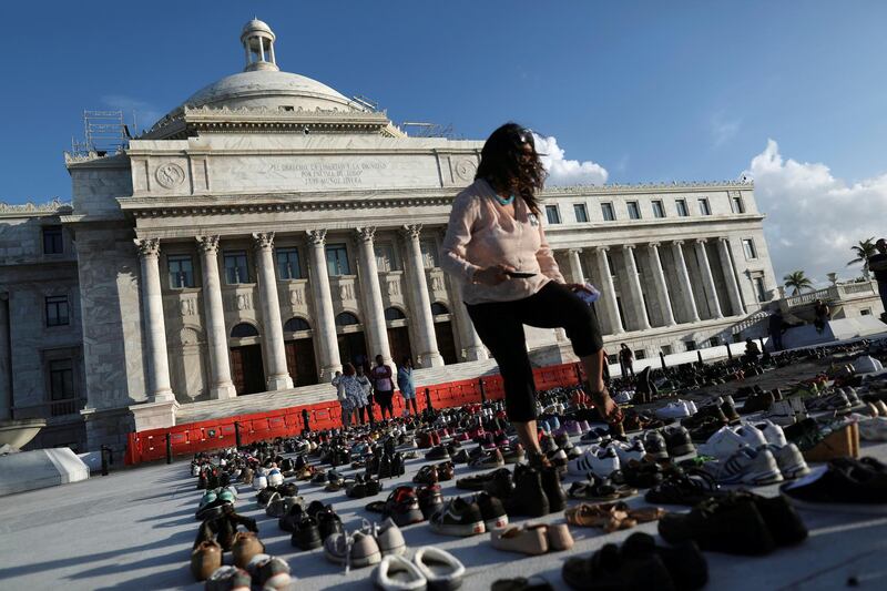 A woman walks among hundreds of pairs of shoes displayed at the Capitol to pay tribute to Hurricane Maria's victims in San Juan, Puerto Rico. Alvin Baez / Reuters