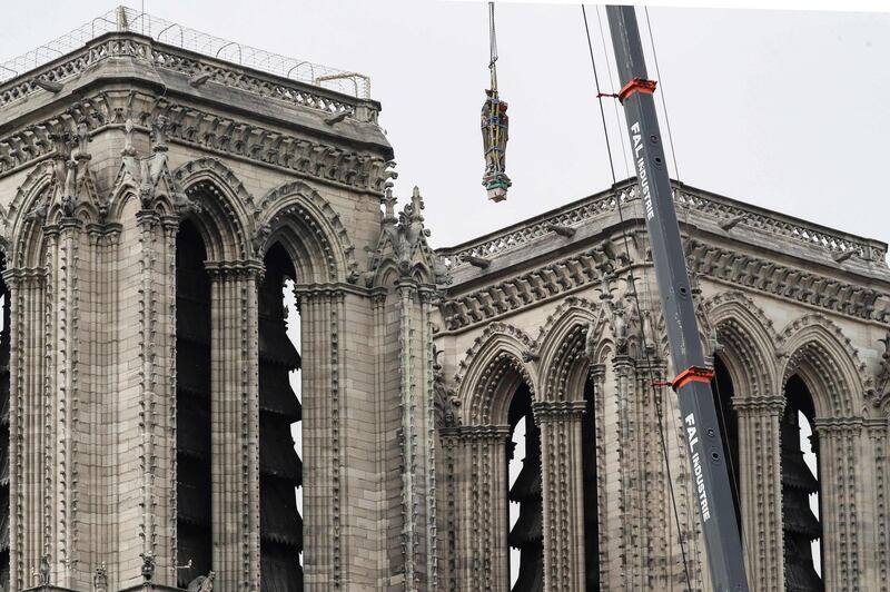 A statue is removed from Notre-Dame de Paris cathedral in Paris one week after a fire devastated the cathedral.  AFP