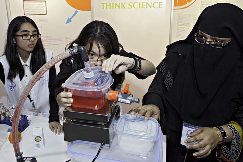 From left, Isabel Garrovillas, Jeremie Pearl Cruz and Rahimunisa Sami Khan, from the American International School in Dubai, work on their project, safe fabric dye from orange peels, during the Think Science fair at Dubai World Trade Centre. Jaime Puebla / The National 
