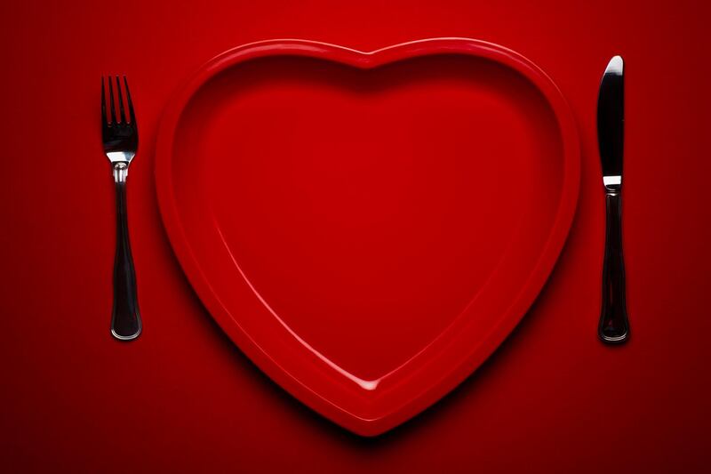 Heart shaped plastic plate on red background with fork and knife. Getty Images