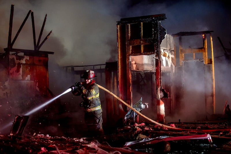 Firefighter Josh Cole charges forward into rubble and debris to extinguish a large fire that destroyed a business and shut down a busy thoroughfare in Davison, Michigan. AP