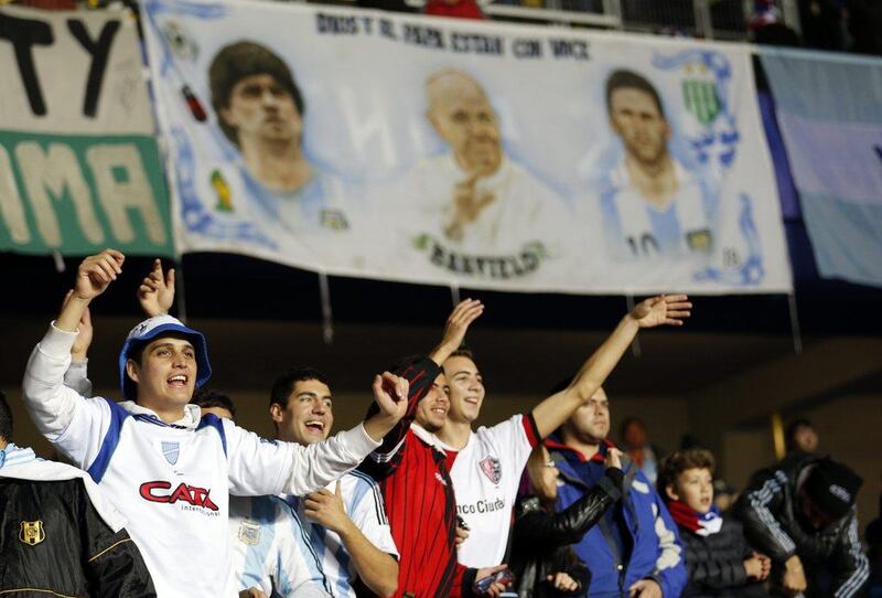 Argentina fans cheer on their team under a banner depicting Diego Maradona, Pop Francis and Lionel Messi during the Copa America semi-final on Tuesday night. Silvia Izquierdo / AP