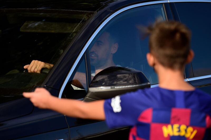 A young Barcelona supporter sporting Lionel Messi's jersey gestures as Barcelona's Spanish midfielder Sergio Busquets arrives. AFP