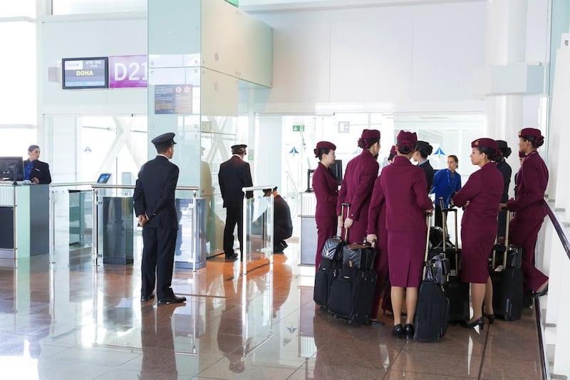 Qatar airways pilots and cabin staff wait at an airport departure gate before boarding a flight. Loop Images / UIG via Getty Images