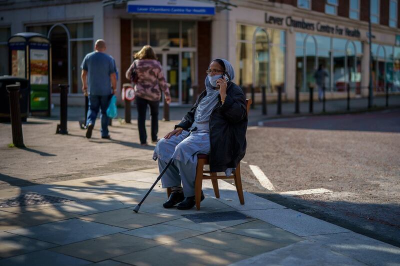 Since easing its first nationwide lockdown in May, England has imposed localised lockdown rules on towns across the Midlands and North. A shopkeeper keeps a socially distanced watch on her shop from a chair on the pavement in Bolton.  Getty Images