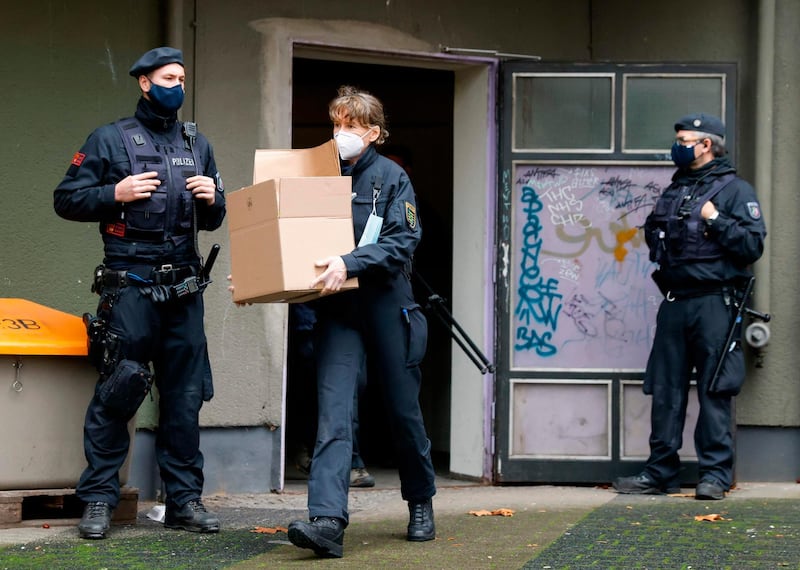A police officer carries boxes filled with evidence out of a building in Berlin's Kreuzberg district during raids. AFP