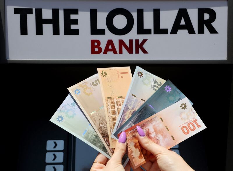 A Lebanese activist displays fake banknotes called “Lollars”, in front of a mock ATM, during a stunt to denounce the high-level of corruption that has wrecked the country. AFP