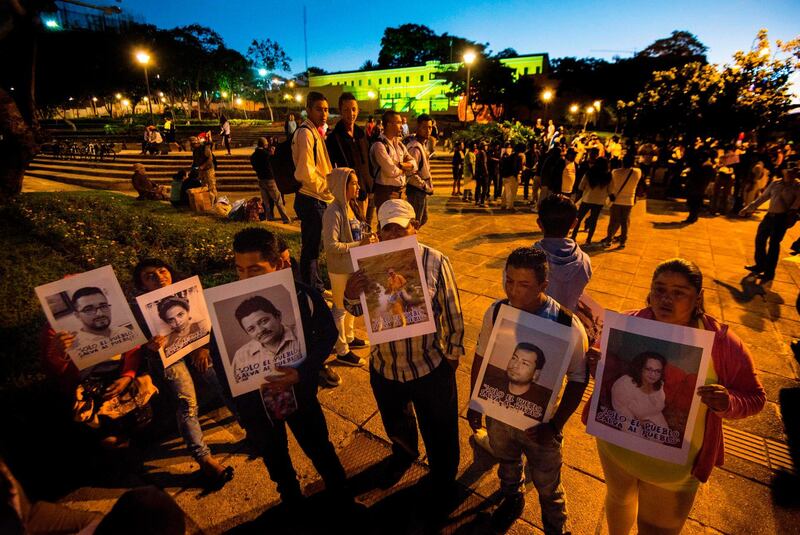 Nicaraguans living in Costa Rica hold pictures of their loved ones at Plaza de la Democracia in San Jose, Costa Rica on December 16, 2018, as they prepare to leave in a bus caravan to the border between the two countries to protest against Daniel Ortega's regime. / AFP / Ezequiel BECERRA
