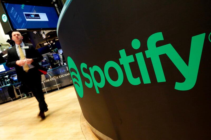 FILE - In this Tuesday, April 3, 2018 file photo, a trading post sports the Spotify logo on the floor of the New York Stock Exchange. Music streaming service Spotify says the number of its paying subscribers has hit 100 million for the first time, up 32% on the year and almost twice the latest figures for Apple Music. The Stockholm-based company called the figure, which was reached during the first three months of 2019, "an important milestone." (AP Photo/Richard Drew, File)