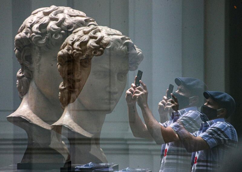 A visitor is reflected in glass as he takes a picture of a replica of the head of Michelangelo's sculpture "David" at the National Museum of Fine Arts Museum on its opening day after closing for over half a year due to the lockdown to curb the spread of COVID-19 in Santiago, Chile. AP Photo