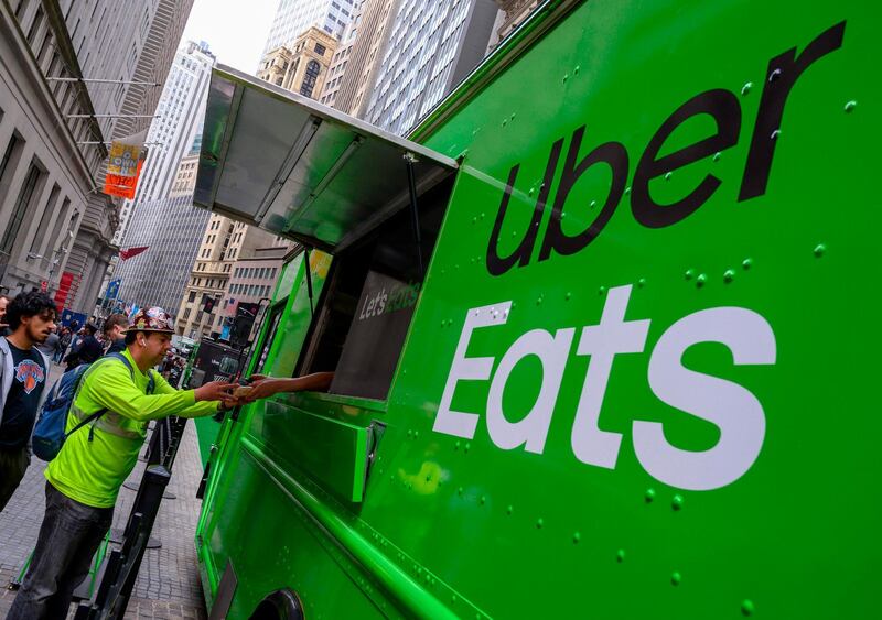 (FILES) In this file photo taken on May 10, 2019, people buy food from an Uber Eats truck in front of the New York Stock Exchange in New York. Uber has made a takeover bid for meal delivery group Grubhub, media reports said on May 12, 2020,, sparking a strong rally in shares of the Chicago-based group. Grubhub shares rose more than 20 percent on the reports in The Wall Street Journal and other media. The reports said Uber had made a specific offer for Grubhub but that no agreement had been reached. / AFP / Don EMMERT

