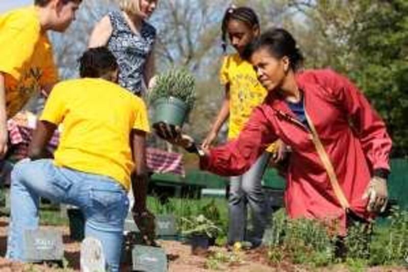 First lady Michelle Obama plants herbs on the White House Kitchen Garden with students from Bancroft Elementary School in Washington, Thursday, April 9, 2009, on the South Lawn of the White House in Washington. (AP Photo/Charles Dharapak)