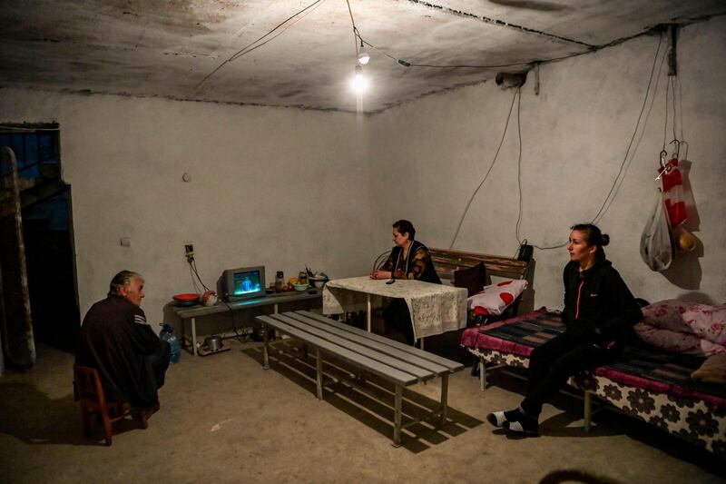 Members of a family watch television in a basement shelter in Martuni. AFP