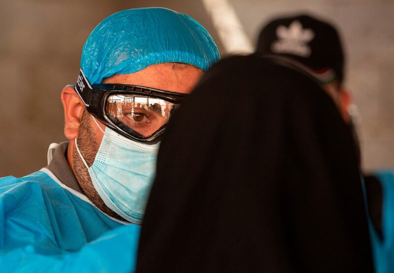 An Iraqi woman, who had been stranded in Iran due to the novel coronavirus pandemic, gets her temperature checked by a health worker upon her arrival to Iraq via the Al-Shalamija border crossing, west of the southern city of Basra.   AFP