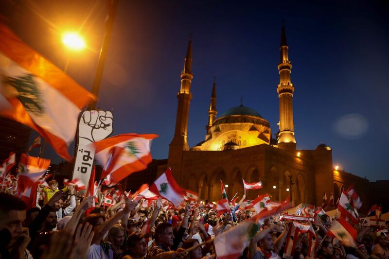 TOPSHOT - Lebanese anti-government protesters wave the national flag during a demonstration in downtown Beirut on November 17, 2019. Thousands of Lebanese took to the streets today, as an unprecedented protest movement which took off on October 17 against the ruling elite deemed corrupt, entered its second month with the country gripped in political and economic uncertainty. / AFP / Patrick BAZ
