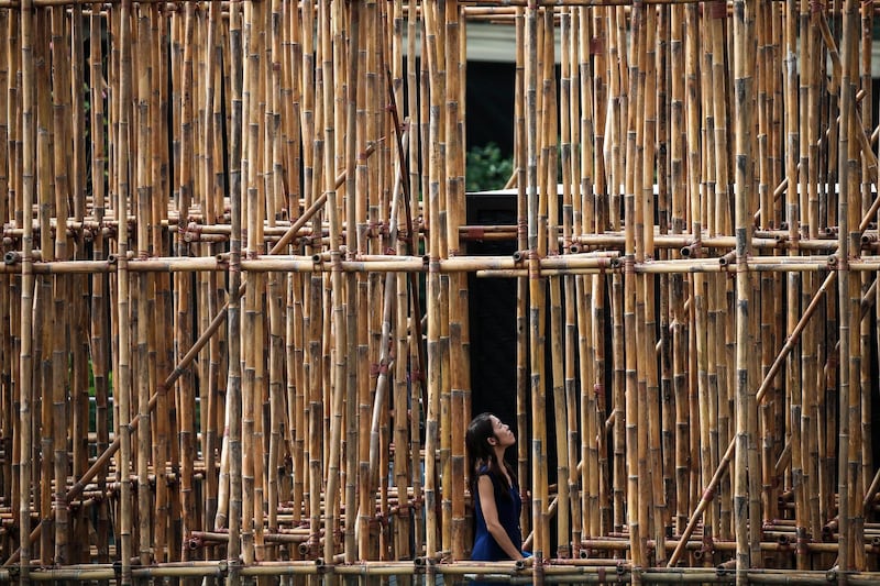 A woman (bottom, centre) looks upwards at the bamboo structure installation titled 'the infinite dimensions of smallness' by Thai artist Rirkrit Tiravanija on display on the roof garden at the National Gallery in Singapore. Wallace Woon / EPA