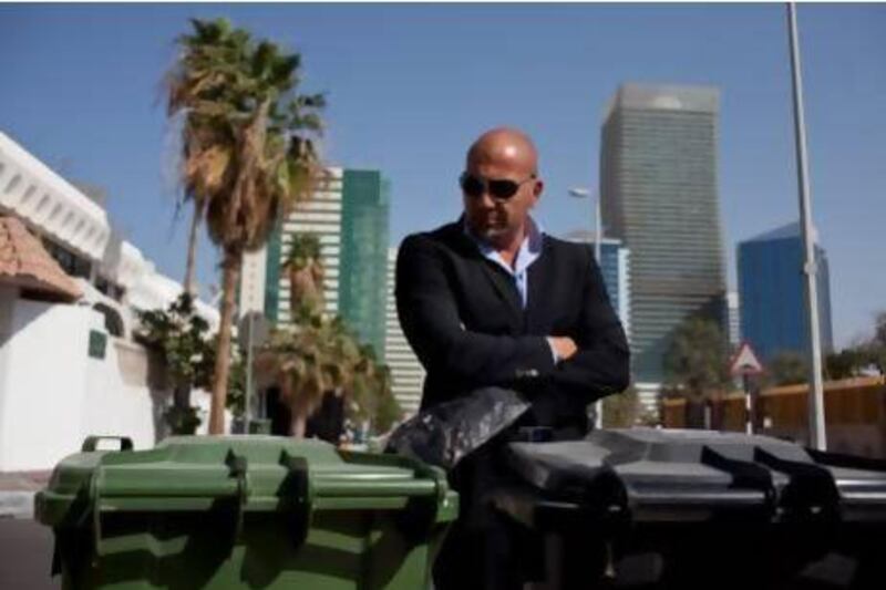 Tareq Altan with his family's recycling bins - green for recyclable waste, black for other rubbish - outside his home in the Khalidiya area of Abu Dhabi. Mr Altan's family recycle their household waste. Silvia Razgova / The National