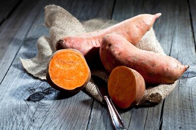 Row sweet potatoand knife on jute, wood