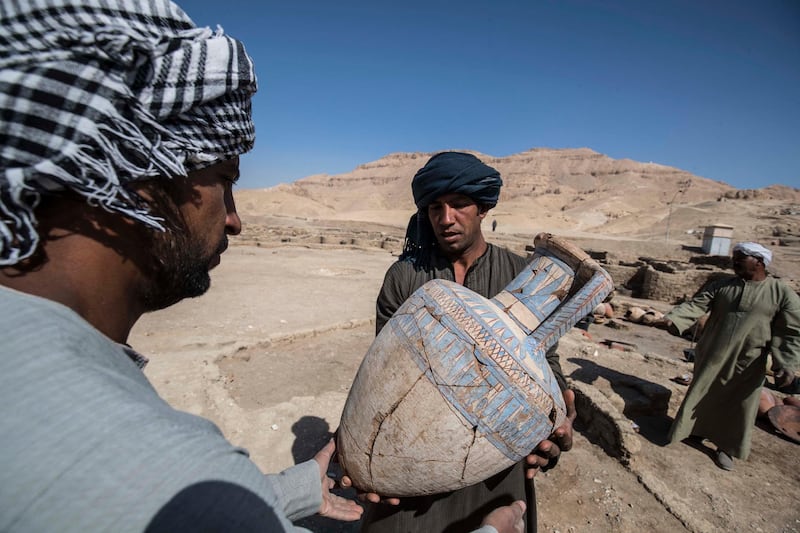 Workers hold a pot found at the site of the ancient city. AFP