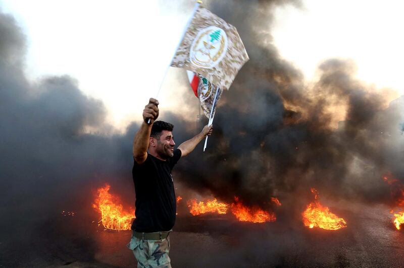 A Lebanese army soldier carries Lebanese Army flags during a protest over a state budget that includes a provision taxing their pensions, in Naameh, south of Beirut, Lebanon. EPA