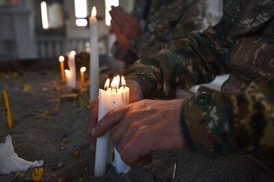 Military volunteers pray in the damaged Ghazanchetsots (Holy Saviour) Cathedral in the historic city of Shusha, some 15 kilometers from the disputed Nagorno-Karabakh province's capital Stepanakert, that was hit by a bomb during the fighting between Armenia and Azerbaijan over the breakaway region, on November 1, 2020. / AFP / Karen MINASYAN
