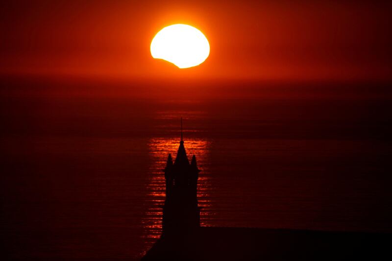 The Saint-They Chapel is seen in silhouette at sunset during a partial solar eclipse, as the moon passes in front of the sun, seen at the Pointe du Van, in Brittany, France. Mal Langsdon / Reuters