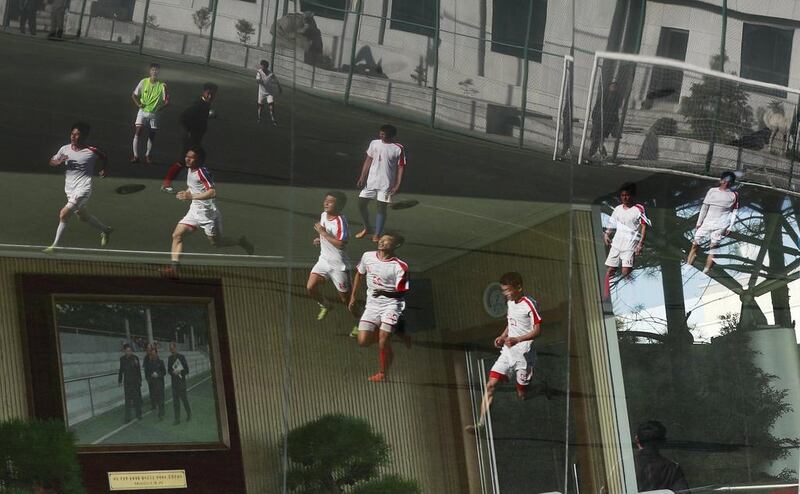North Korean football players training in a field are reflected on a glass window in Pyongyang, North Korea. How Hwee Young / EPA