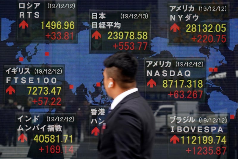 A man looks at an electronic stock board showing Japan's Nikkei 225 index and other country's index at a securities firm in Tokyo Friday, Dec. 13, 2019. Shares likewise jumped Friday in Asia following fresh all-time highs overnight on Wall Street spurred by optimism that the U.S. and China are close to reaching a deal to end their costly trade war. (AP Photo/Eugene Hoshiko)