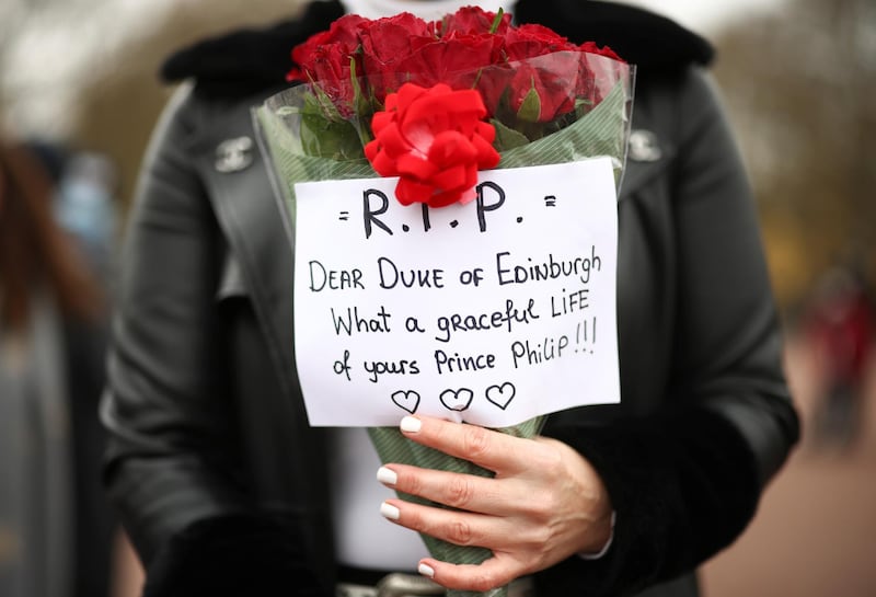 A member of the public person holds a floral tribute to Prince Philip outside Buckingham Palace, London. Reuters