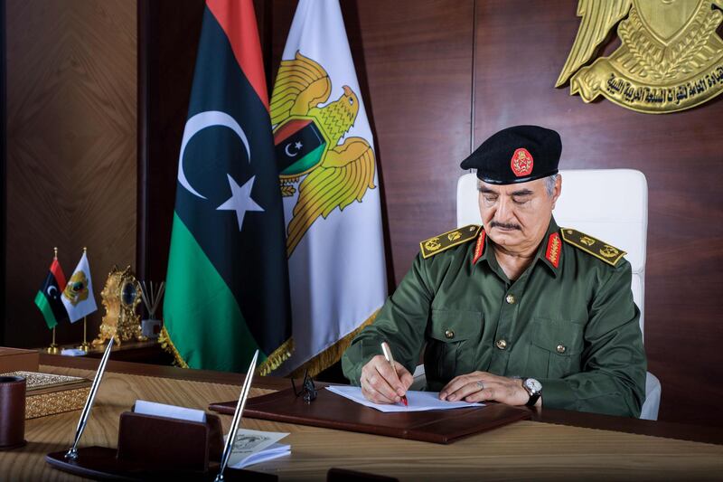 A handout picture released by the Media Office of the Libyan National Army General Command shows Libyan General Khalifa Haftar writing on a paper at his desk in Benghazi. Haftar announced a conditional lifting of a months-long blockade on oilfields and ports by his forces. AFP