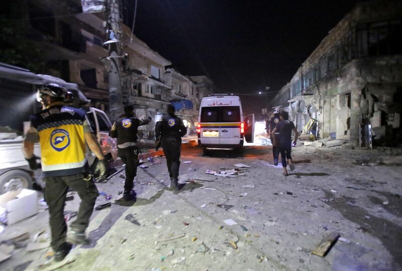 White Helmets rescue volunteers gather at the site of an air strike on a market in the town of Maarat al-Numan on May 21, 2019. At least 12 people were killed and 18 others wounded in overnight strikes on the Idlib  town of Maarat al-Numan, the Britain-based Syrian Observatory for Human Rights said.  / AFP / Abdulaziz KETAZ
