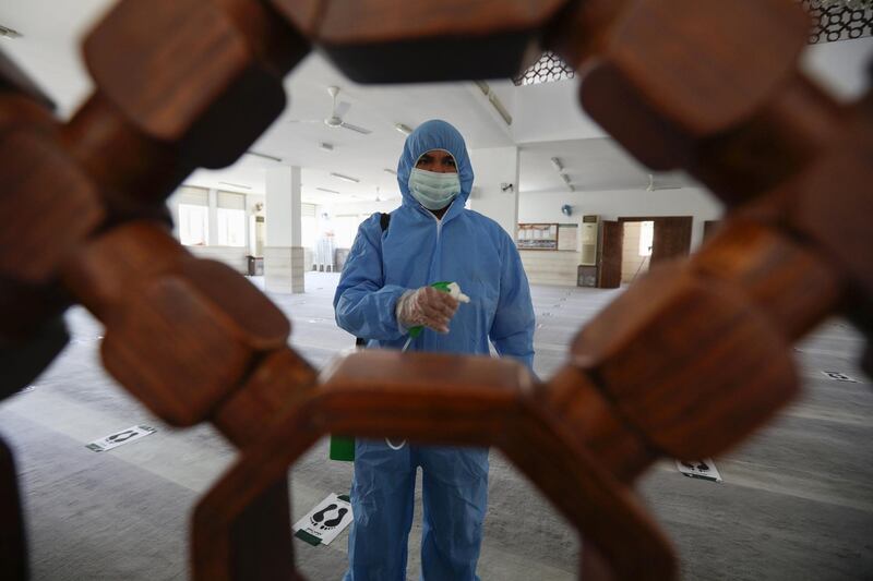 A worker wears a protective suit while spraying disinfectant in a mosque in Amman, Jordan.  REUTERS