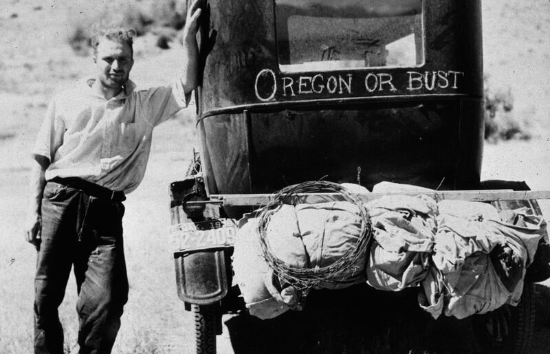 Vernon Evans standing next to his car on Highway Ten near Missoula, Montana. His family are on the way to Washington looking for work hop picking, the sign on the car reads 'Oregon Or Bust'.   (Photo by Arthur Rothstein/Getty Images)