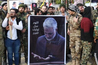 Member of Syria's military gather in the central Saadallah al-Jabiri square in the northern Syrian city of Aleppo on January 7, 2020, to mourn and condemn the death of Iranian military commander Qasem Soleimani (portrait), and nine others in a US air strike in Baghdad.  / AFP / -
