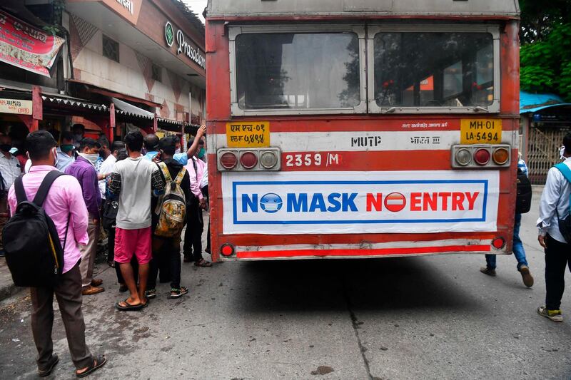 Passengers wearing face masks as a preventive measure against the coronavirus wait to board a bus in Mumbai.  AFP