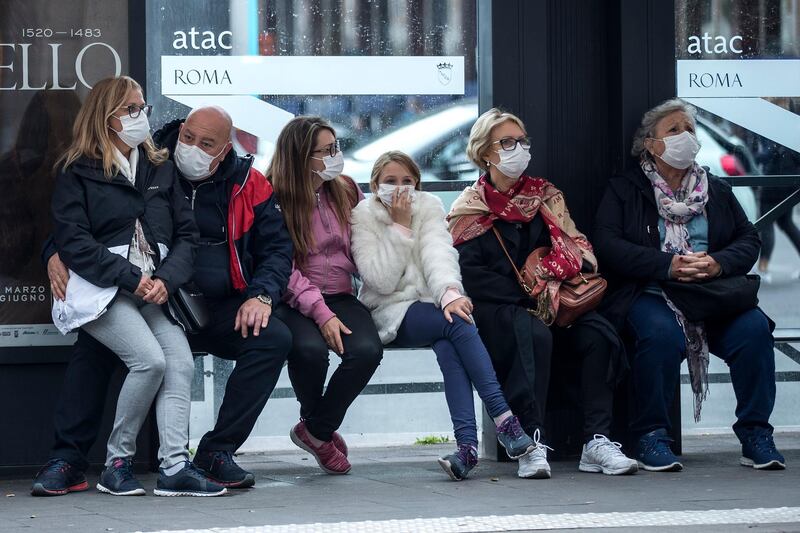 People wait at a bus stop, in Rome, Monday, March 9, 2020. AP