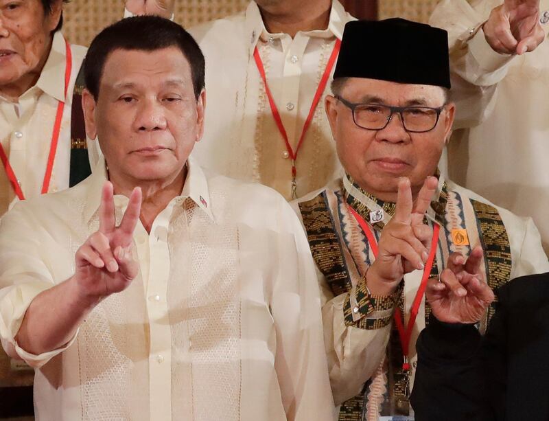 FILE - In this Friday, Feb. 22, 2019, file photo, Moro Islamic Liberation Front chairman Murad Ebrahim, right, and Philippine President Rodrigo Duterte flash peace signs following oath-taking ceremony for the creation of the Bangsamoro Transition Authority (BTA) at the Presidential Palace in Manila, Philippines. Former Muslim guerrillas took over governance of a poverty- and conflict-wracked Muslim autonomous region on Tuesday, Feb. 26, 2019 under a peace deal partly aimed at combating Islamic State group-aligned militants in the southern Philippines. Ebrahim assumed leadership in a ceremony in Cotabato city of an 80-member transition authority dominated by his guerrilla group to govern a five-province region called Bangsamoro. (AP Photo/Bullit Marquez)