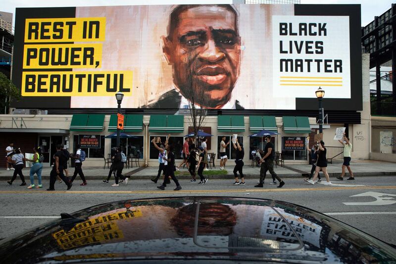 People walk past an electronic sign with an image of George Floyd near Centennial Olympic Park in Atlanta, Georgia. Getty Images