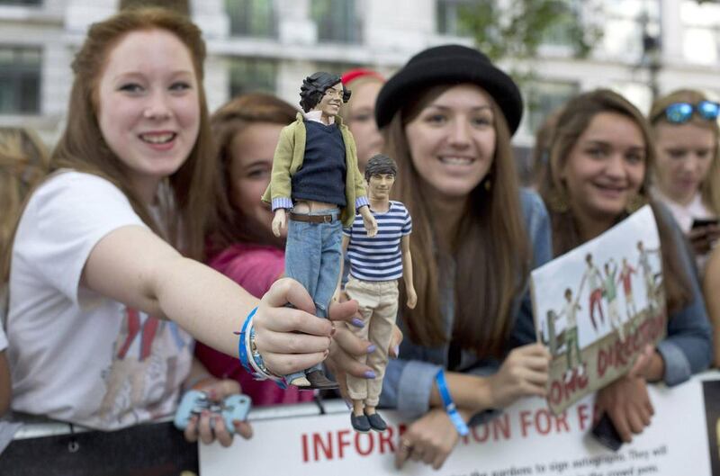 Fans hold dolls depicting One Direction band members Harry Styles and Louis Tomlinson, as they wait for the premiere of the film One Direction: This is Us, in London on 20 August, 2013. Reuters