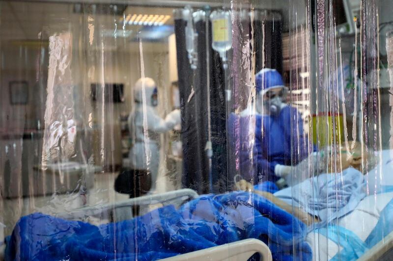 A medic treats a patient infected with coronavirus, at a hospital in Tehran, Iran. A member of a council that advises Iran's supreme leader died Monday after falling sick from the new coronavirus, becoming the first top official to succumb to the illness striking both citizens and leaders of the Islamic Republic. Mizan News Agency via AP