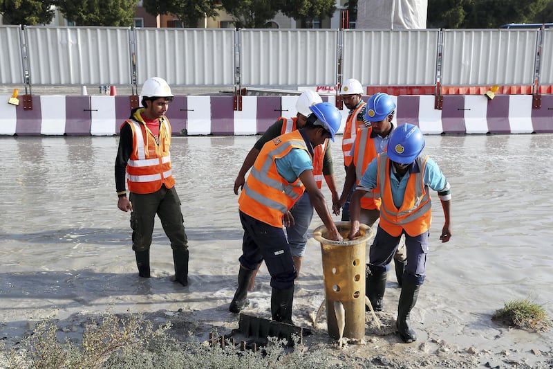 DUBAI , UNITED ARAB EMIRATES , JAN 09 – 2018 :- Workers at the under construction Dubai Metro site clearing the blocked drainage because of last night rain in Discovery Gardens area in Dubai.  (Pawan Singh / The National) For News. 
