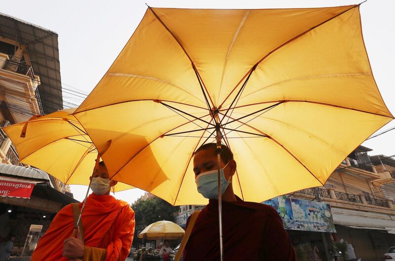 Buddhist monks wear face masks as they receive alms from devotees in Phnom Penh, Cambodia. AP Photo