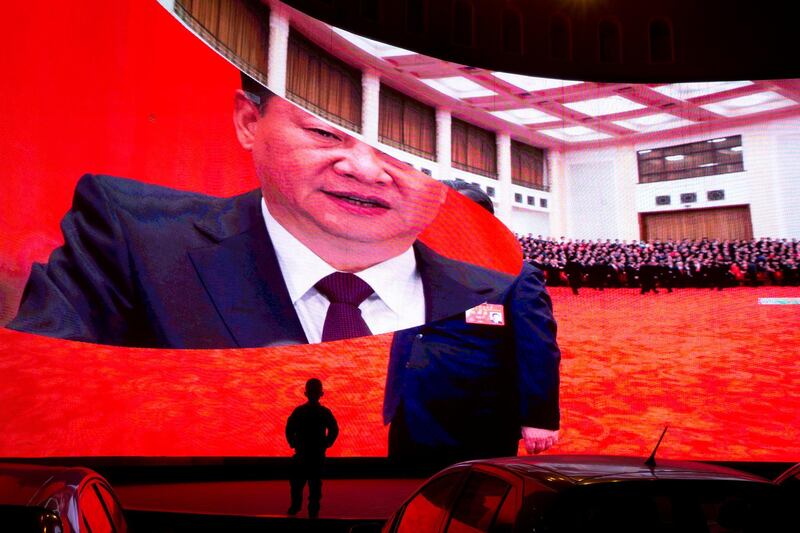 In this Dec. 3, 2018, photo, a child stands near a large screen showing photos of Chinese President Xi Jinping near a carpark in Kashgar in western China's Xinjiang region. Across the Xinjiang region, a growing number of internment camps have been built, where by some estimates 1 million Muslims are detained, forced to give up their language and their religion and subject to political indoctrination. Now, the Chinese government is also forcing some detainees to work in manufacturing and food industries. Some of them are within the internment camps; others are privately owned, state-subsidized factories where detainees are sent once they are released. (AP Photo/Ng Han Guan)