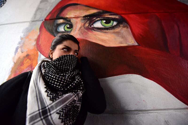 An Iraqi woman stands next to a wall painted with a graffiti near the Al Tahrir square in central Baghdad.  EPA