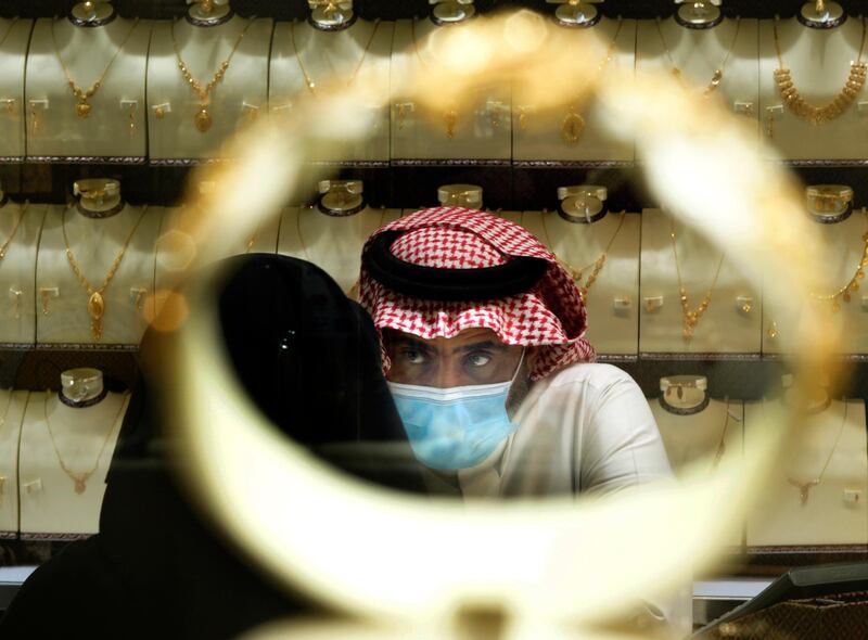 A Saudi vendor is seen through a bracelet as a woman buys jewels at the gold market a day before the expected increase of VAT from 5% to 15%, in Jiddah, Saudi Arabia. AP Photo