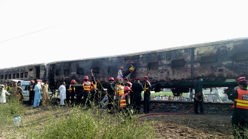 Rescue workers shift the bodies of the victims after a fire engulfed a passenger train near Rahim Yar Khan, Pakistan.   EPA