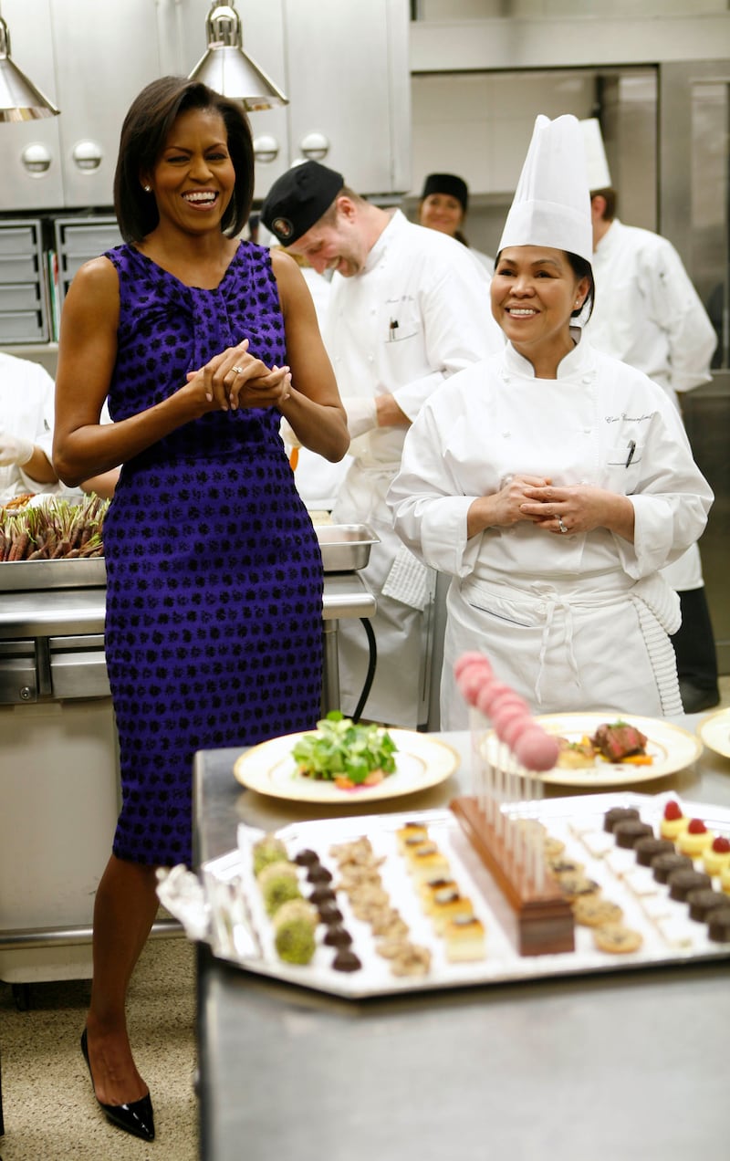 Michelle Obama, who was first lady at the time, laughs with Ms Comerford, right, as she gives a kitchen preview for a dinner at the White House in 2009. Reuters