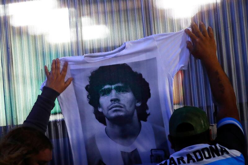 Fans hold a jersey with the face of Diego Maradona at Clínica Olivos. Getty Images