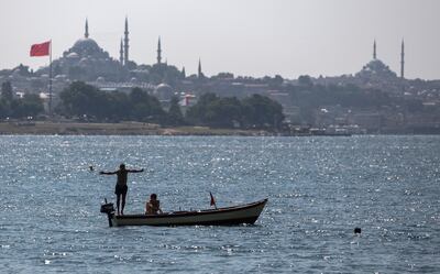 A man jumps into the Bosphorus to cool off during warm weather in front of the Suleymaniye Mosque. EPA